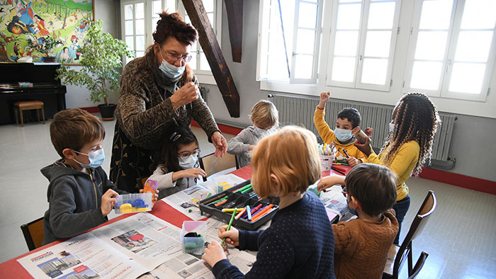 Travail collectif d'enfants à la table avec adulte debout